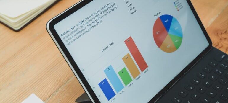 People around a laptop that shows infographs and pie charts.