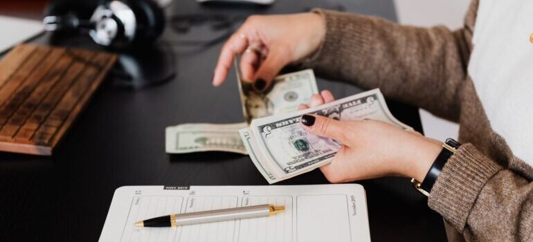 A woman counting money over a notebook.