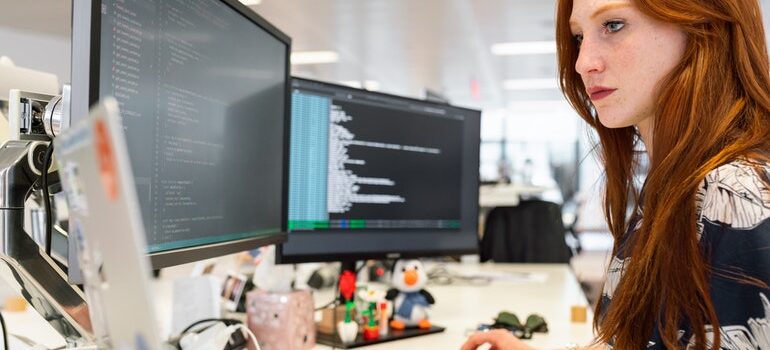 Woman working on a computer with three screens.
