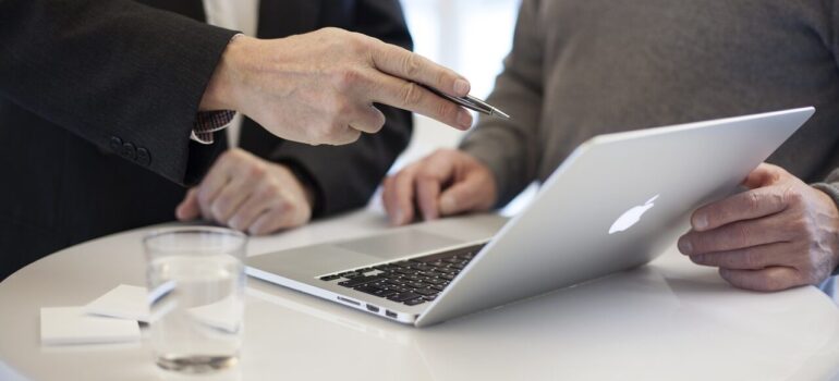 A professional pointing to a laptop during a consultation.