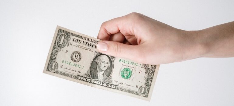 A person handing over a dollar bill.