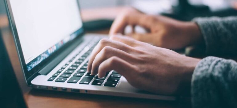A person typing on their laptop keyboard.