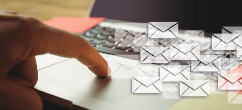 Image of finger on laptop touchpad with email icons.