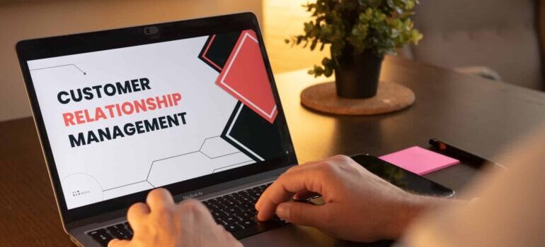 A person typing on a laptop, with the words Customer Relationship Managment on the screen.