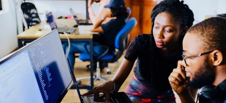 Two people behind a desktop PC screen.