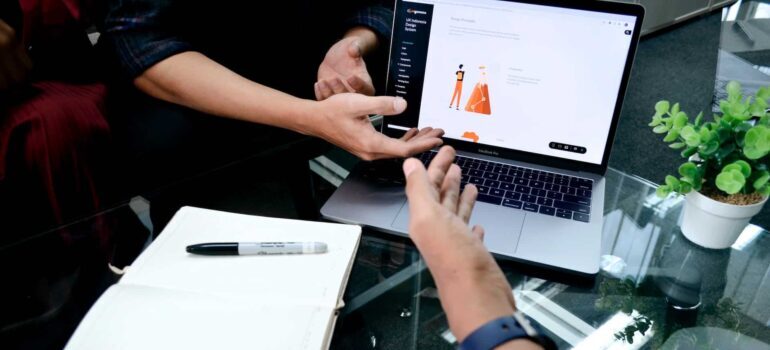 Four hands in front of a laptop.