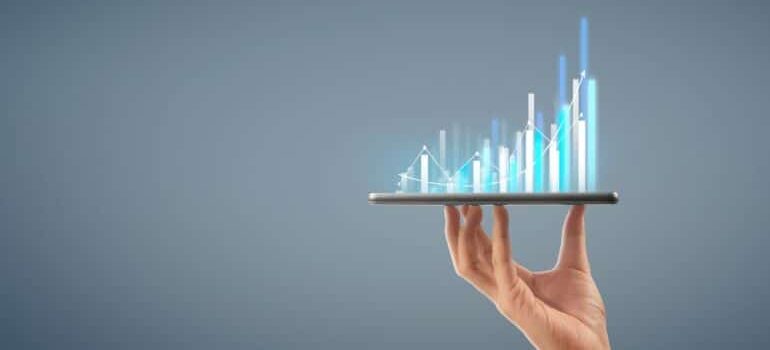 Hand holding a smartphone with growth graph emerging from it. | sales collateral management in your CRM