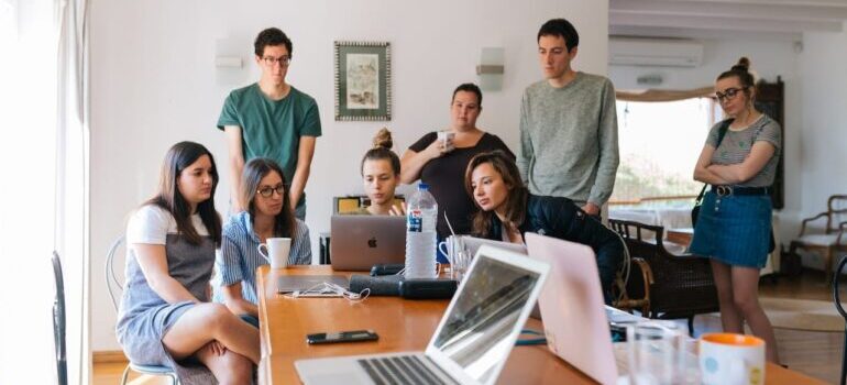 A bunch of people gathered around a computer.