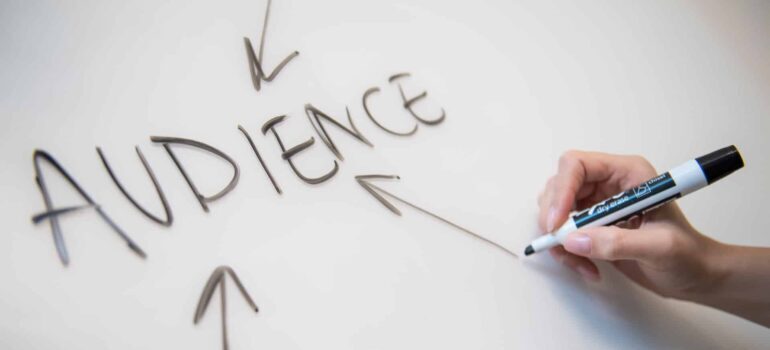 A person writing on a chalkboard with a black marker.