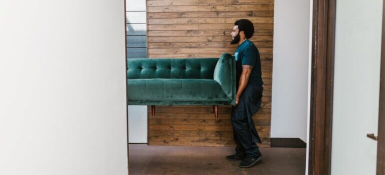 A mover carrying a couch.